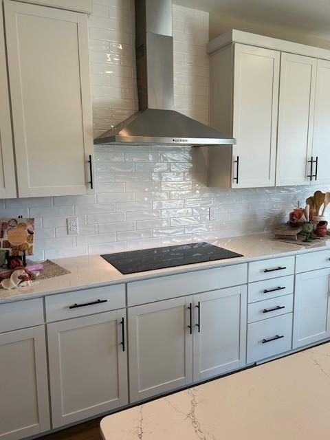131 W Cassa Way, Mount Juliet, TN 37122 - kitchen with wall chimney range hood, backsplash, black electric cooktop, and white cabinetry