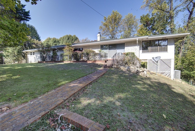 view of front of property featuring a front lawn, a chimney, and brick siding