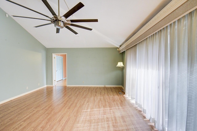 spare room with vaulted ceiling, a ceiling fan, wood finished floors, and baseboards