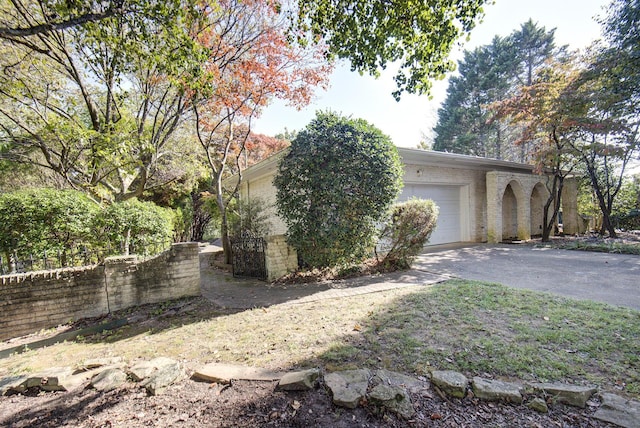 view of property exterior featuring asphalt driveway, a garage, and brick siding