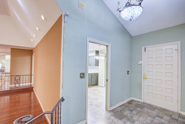 entrance foyer with high vaulted ceiling, a chandelier, and baseboards