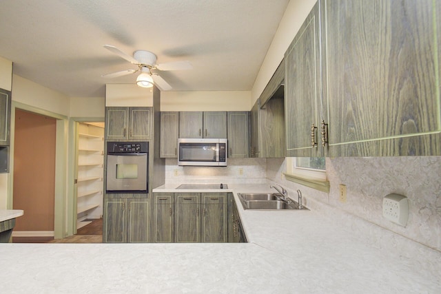 kitchen with stainless steel appliances, a sink, a ceiling fan, light countertops, and decorative backsplash