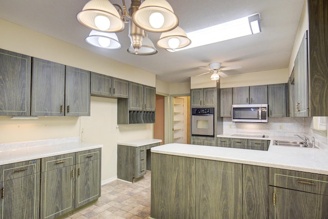 kitchen featuring appliances with stainless steel finishes, a sink, a peninsula, ceiling fan, and light countertops