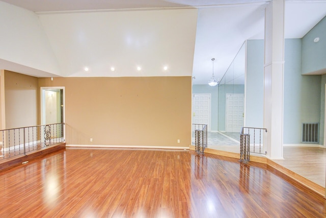 empty room with wood finished floors, lofted ceiling, baseboards, and recessed lighting