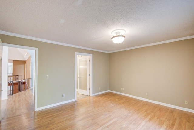 spare room featuring light wood-style flooring, ornamental molding, a textured ceiling, and baseboards