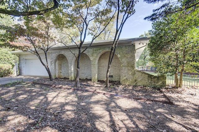 view of side of property featuring a garage, driveway, and brick siding
