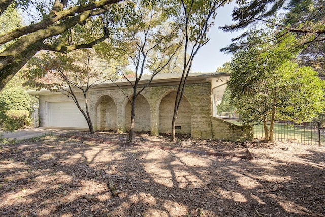 view of side of home with a garage, dirt driveway, and brick siding