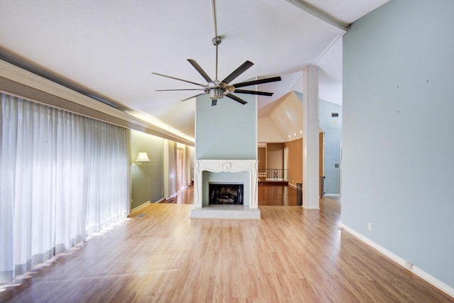 unfurnished living room with vaulted ceiling, a ceiling fan, wood finished floors, a fireplace with raised hearth, and baseboards