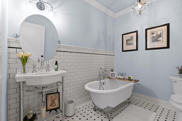1440 Bowman Rd, Hixson, TN 37343 - bathroom with tile walls, a freestanding tub, toilet, a wainscoted wall, and a sink