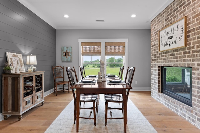 1440 Bowman Rd, Hixson, TN 37343 - dining area with light wood-type flooring, baseboards, recessed lighting, a brick fireplace, and wood walls