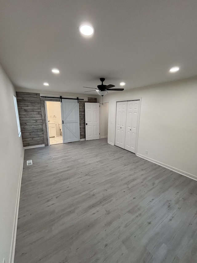 3221 New Towne Rd, Antioch, TN 37013 - unfurnished bedroom with baseboards, a barn door, recessed lighting, wood finished floors, and ceiling fan