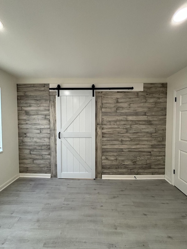 3221 New Towne Rd, Antioch, TN 37013 - unfurnished room featuring baseboards, wood finished floors, wood walls, and a barn door