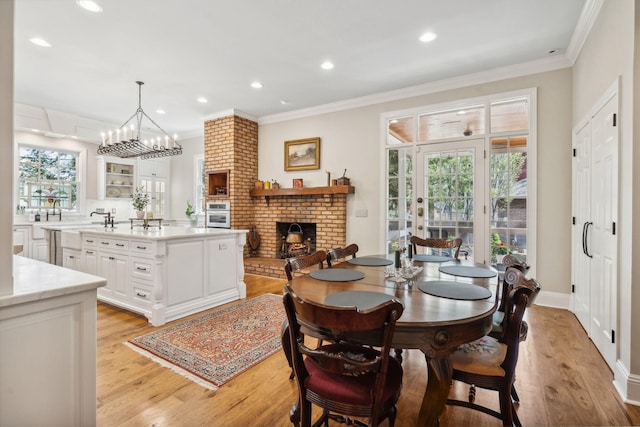 901 Fair St, Franklin, TN 37064 - dining space with a brick fireplace, ornamental molding, light wood finished floors, recessed lighting, and a chandelier
