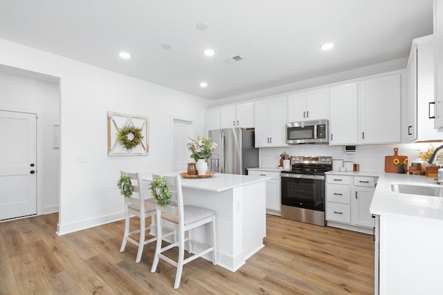 108 Model Ct, Columbia, TN 38401 - kitchen with stainless steel appliances, a kitchen island, a kitchen bar, a sink, and light wood finished floors