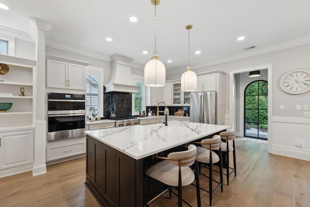 2143 White Poplar Ct, Murfreesboro, TN 37130 - kitchen with appliances with stainless steel finishes, custom exhaust hood, a breakfast bar area, a kitchen island with sink, and light stone countertops