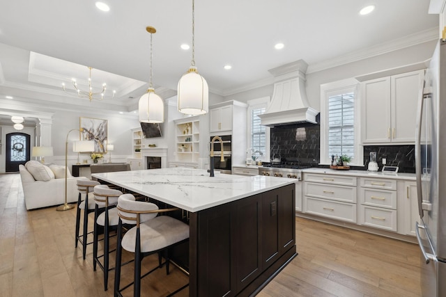 2143 White Poplar Ct, Murfreesboro, TN 37130 - kitchen featuring custom range hood, open floor plan, a fireplace, backsplash, and white cabinets