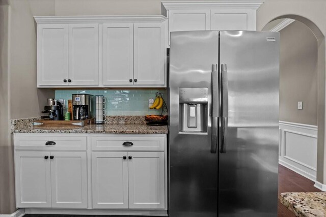 7211 Deervalley Dr, Fairview, TN 37062 - kitchen featuring stainless steel fridge, stone countertops, white cabinets, arched walkways, and a wainscoted wall