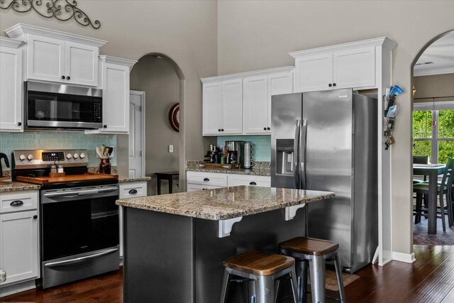 7211 Deervalley Dr, Fairview, TN 37062 - kitchen with appliances with stainless steel finishes, arched walkways, dark wood-type flooring, backsplash, and white cabinets