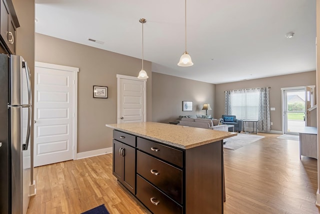 5008 Fennel Ct, Spring Hill, TN 37174 - kitchen featuring freestanding refrigerator, light wood-style flooring, dark brown cabinets, hanging light fixtures, and a center island