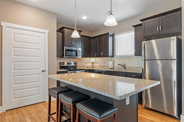 5008 Fennel Ct, Spring Hill, TN 37174 - kitchen featuring appliances with stainless steel finishes, light stone countertops, a sink, a kitchen breakfast bar, and dark brown cabinets