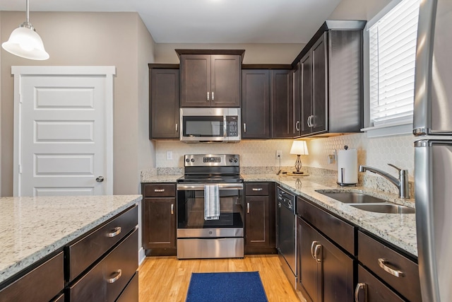 5008 Fennel Ct, Spring Hill, TN 37174 - kitchen featuring appliances with stainless steel finishes, a sink, light wood-style flooring, dark brown cabinets, and backsplash
