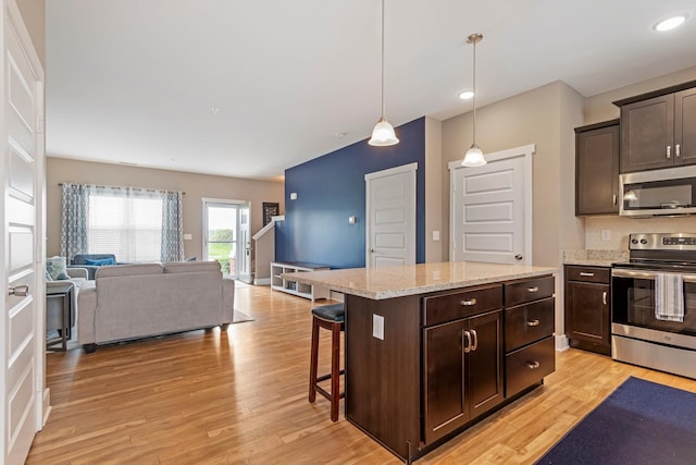 5008 Fennel Ct, Spring Hill, TN 37174 - kitchen featuring stainless steel appliances, dark brown cabinets, open floor plan, light wood-type flooring, and light stone countertops