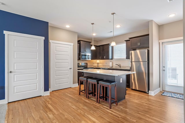 5008 Fennel Ct, Spring Hill, TN 37174 - kitchen with stainless steel appliances, a kitchen island, dark brown cabinetry, baseboards, and light wood finished floors