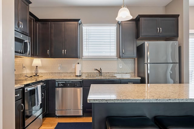 5008 Fennel Ct, Spring Hill, TN 37174 - kitchen with appliances with stainless steel finishes, a sink, light wood-style flooring, light stone countertops, and decorative backsplash