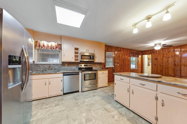 206 Crestland Dr, Columbia, TN 38401 - kitchen with appliances with stainless steel finishes, a sink, wood walls, a skylight, and backsplash