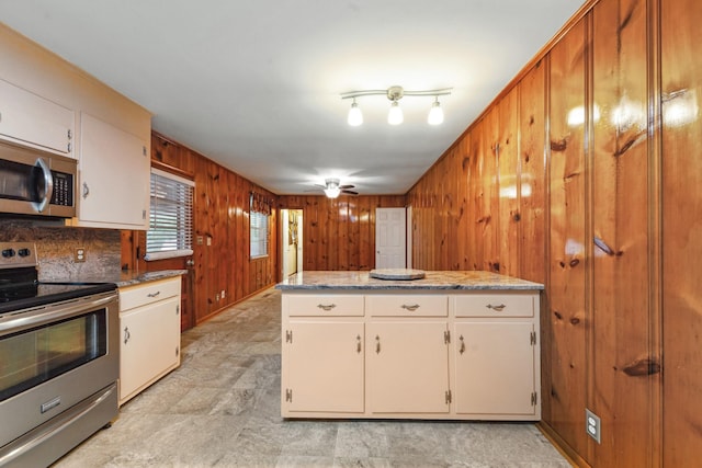 206 Crestland Dr, Columbia, TN 38401 - kitchen with appliances with stainless steel finishes, wood walls, white cabinetry, and a ceiling fan