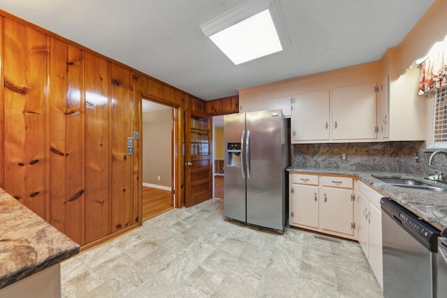 206 Crestland Dr, Columbia, TN 38401 - kitchen featuring appliances with stainless steel finishes, a sink, white cabinets, wood walls, and decorative backsplash
