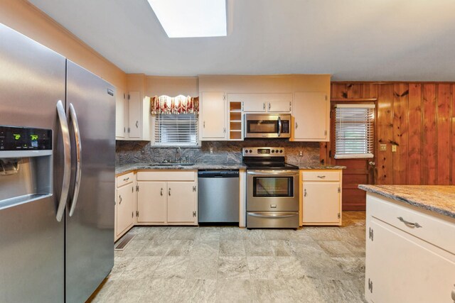 206 Crestland Dr, Columbia, TN 38401 - kitchen featuring appliances with stainless steel finishes, a sink, a skylight, tasteful backsplash, and light stone counters