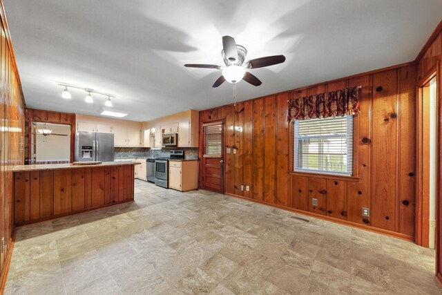 206 Crestland Dr, Columbia, TN 38401 - kitchen with appliances with stainless steel finishes, wooden walls, a peninsula, a ceiling fan, and backsplash
