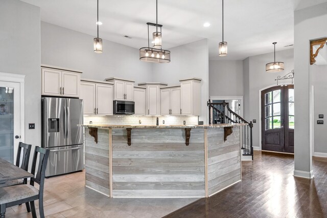 1161 Reda Dr, Clarksville, TN 37042 - kitchen featuring stainless steel fridge with ice dispenser, a high ceiling, decorative backsplash, light stone countertops, and a kitchen breakfast bar