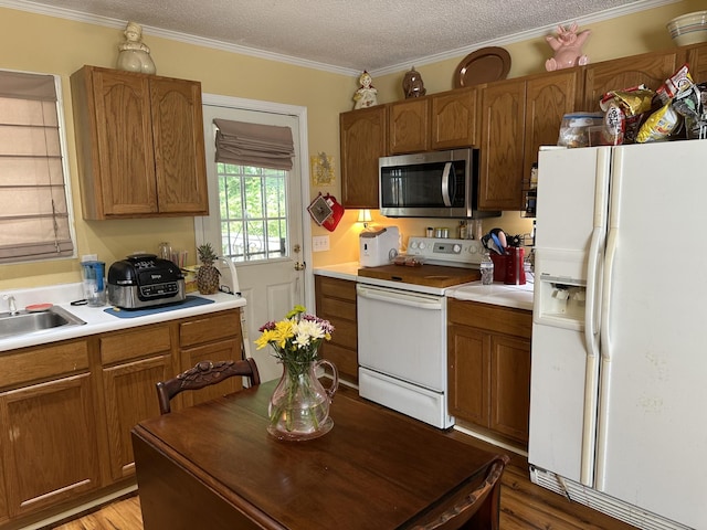 1140 Brittany Park Ln, Antioch, TN 37013 - kitchen with white appliances, a sink, brown cabinetry, light wood finished floors, and a textured ceiling