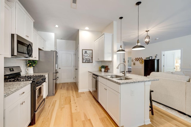 979 Carnation Dr, Spring Hill, TN 37174 - kitchen with stainless steel appliances, a sink, open floor plan, light wood-type flooring, and a kitchen bar