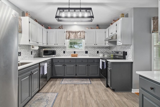 6928 Hoover Mason Ln, Mount Pleasant, TN 38474 - kitchen with gray cabinetry, appliances with stainless steel finishes, under cabinet range hood, and light wood-style floors