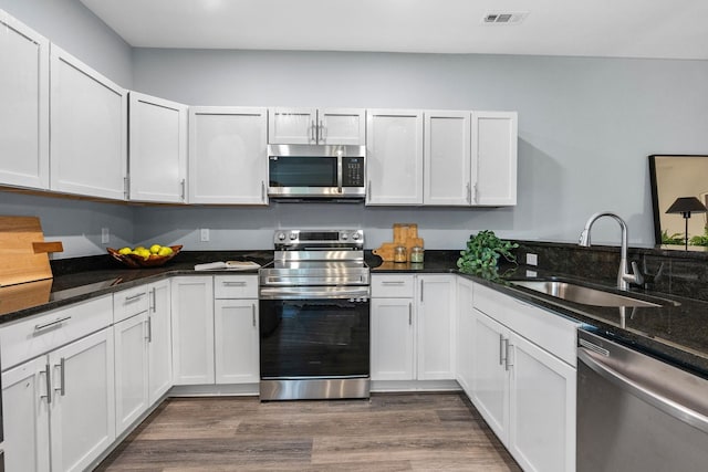 107 Longfellow Ln, Smyrna, TN 37167 - kitchen featuring stainless steel appliances, a sink, white cabinetry, dark wood finished floors, and dark stone countertops