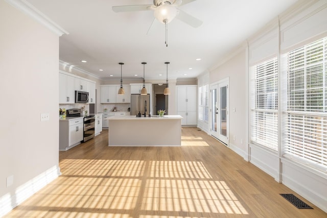 100 Nancy Ct, Hermitage, TN 37076 - kitchen with stainless steel appliances, crown molding, light wood-style flooring, a kitchen island with sink, and light countertops