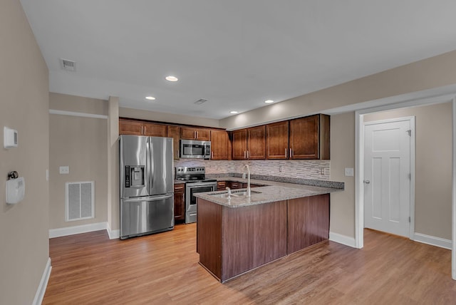 421 Willis Way, Columbia, TN 38401 - kitchen featuring appliances with stainless steel finishes, a sink, a peninsula, tasteful backsplash, and light wood-type flooring