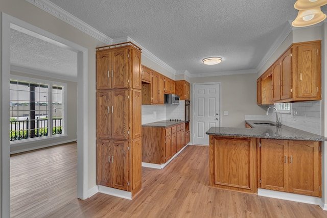 520 Almaville Rd, Smyrna, TN 37167 - kitchen featuring a sink, a textured ceiling, light wood-style floors, a peninsula, and brown cabinetry
