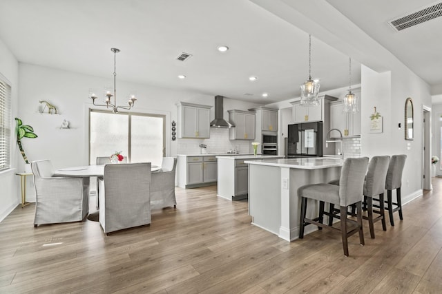 400 Parker Ct, Antioch, TN 37013 - kitchen with gray cabinets, a chandelier, wall chimney range hood, a breakfast bar area, and recessed lighting