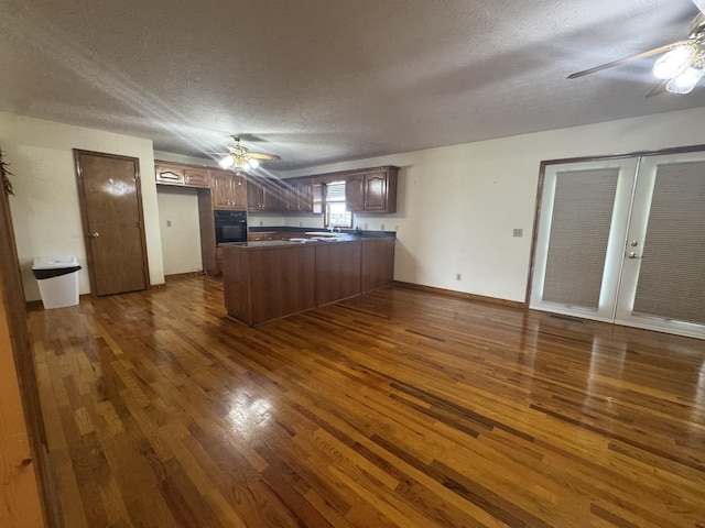 325 Lafayette Ct, Moss, TN 38575 - kitchen featuring a ceiling fan, black oven, a peninsula, dark countertops, and a textured ceiling