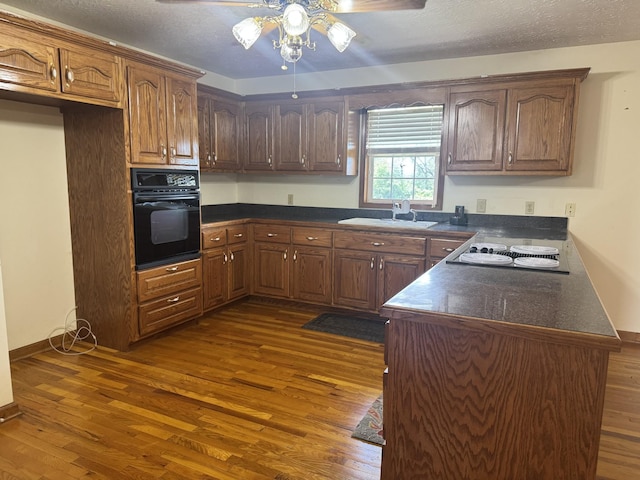 325 Lafayette Ct, Moss, TN 38575 - kitchen with oven, a sink, dark countertops, dark wood-style flooring, and ceiling fan