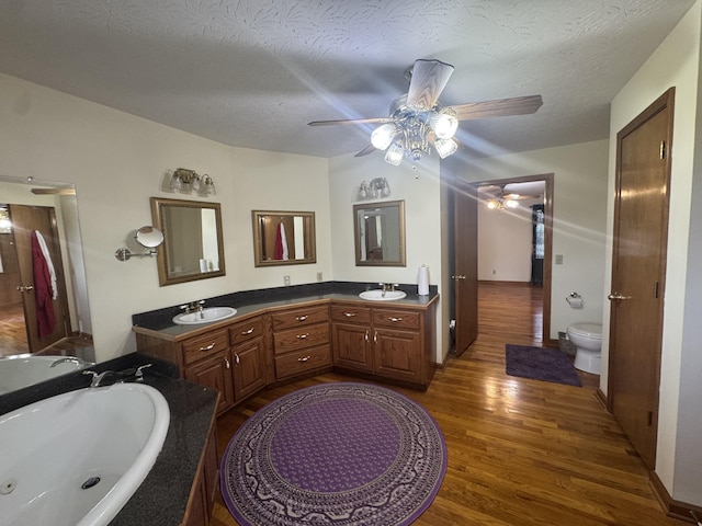 325 Lafayette Ct, Moss, TN 38575 - bathroom featuring ceiling fan, wood finished floors, a whirlpool tub, toilet, and double vanity