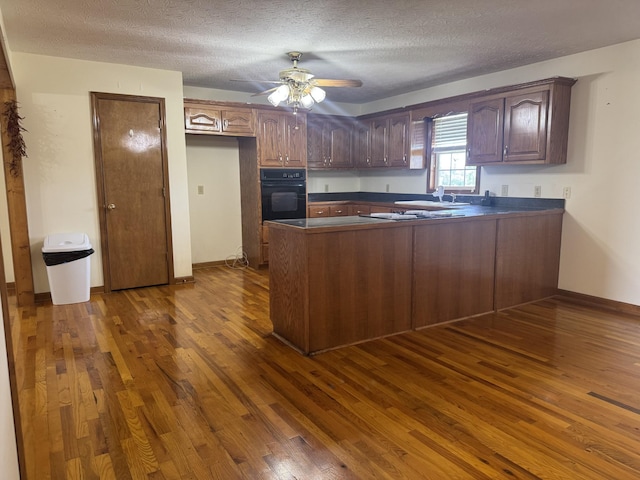 325 Lafayette Ct, Moss, TN 38575 - kitchen with oven, dark countertops, dark wood-style floors, a peninsula, and a textured ceiling