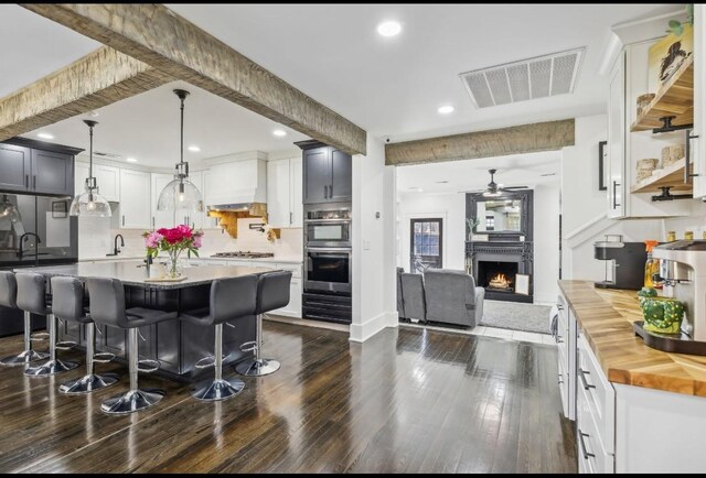 117 Park Cir, Columbia, TN 38401 - kitchen with wooden counters, stainless steel double oven, a warm lit fireplace, a breakfast bar area, and ceiling fan