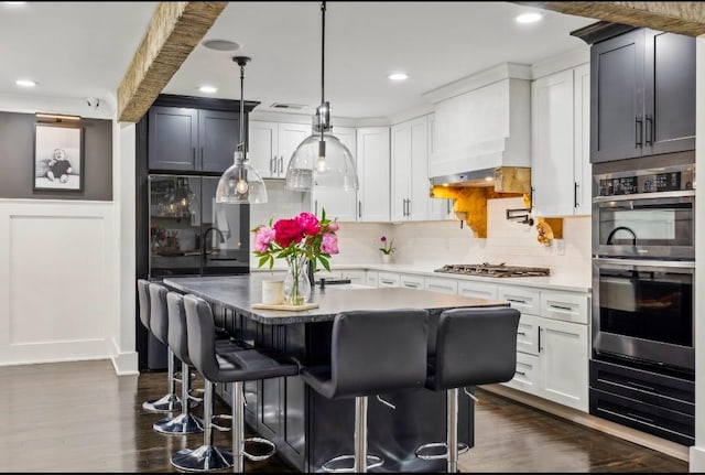 117 Park Cir, Columbia, TN 38401 - kitchen with appliances with stainless steel finishes, a breakfast bar area, decorative backsplash, dark wood-type flooring, and a center island
