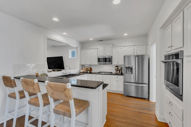 118 Jasper Ave, Franklin, TN 37064 - kitchen with appliances with stainless steel finishes, a sink, a peninsula, a kitchen bar, and white cabinetry