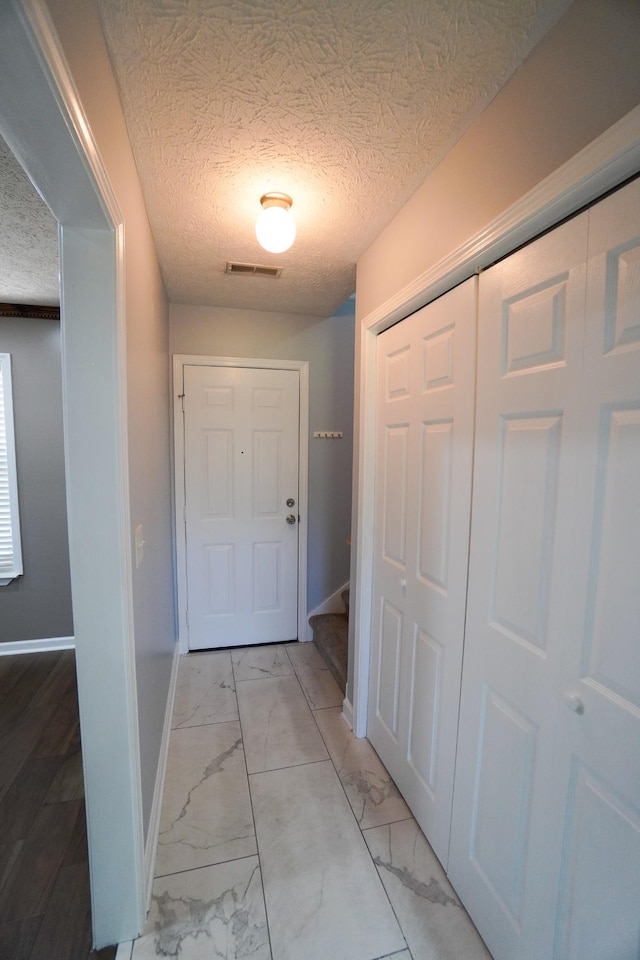 1009 Monticello Pl, Gallatin, TN 37066 - hallway featuring light marble finish floors, a textured ceiling, baseboards, and stairway